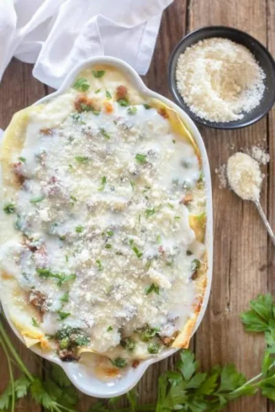 A slice of beef lasagna with visible layers of pasta, meat sauce and melted golden cheese on a white plate