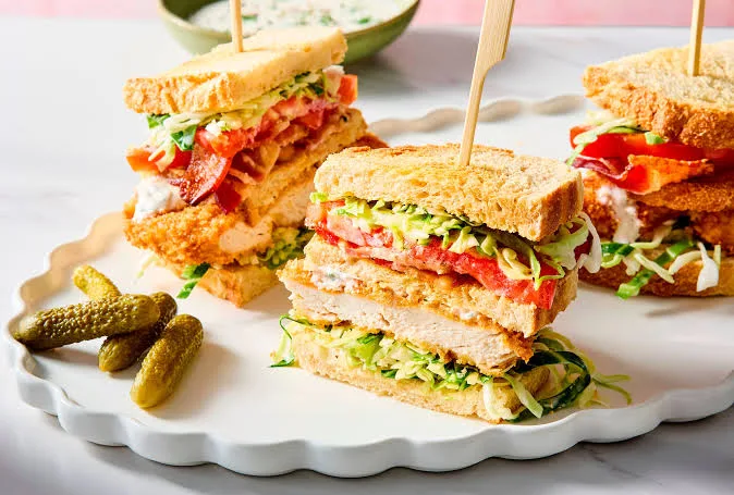 Chicken club sandwich cut into triangles showing layers of chicken, bacon, egg, tomato and lettuce on toasted bread