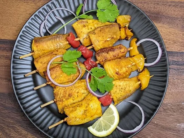 Skewers of golden-red grilled fish tikka with capsicum and onion, served with lemon wedges and mint chutney