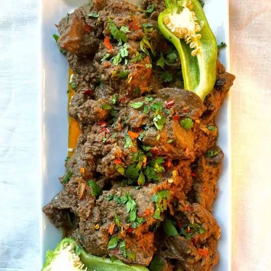 A karahi of Pakistani kaleji masala with liver cubes in thick masala, garnished with ginger, green chilli and coriander