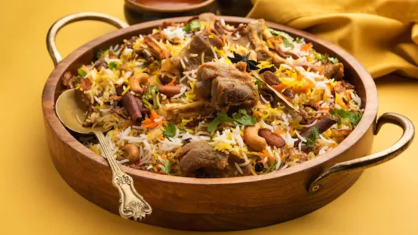 Copper pot of Lucknowi mutton biryani with saffron rice, mutton pieces, fried onions and fresh herbs