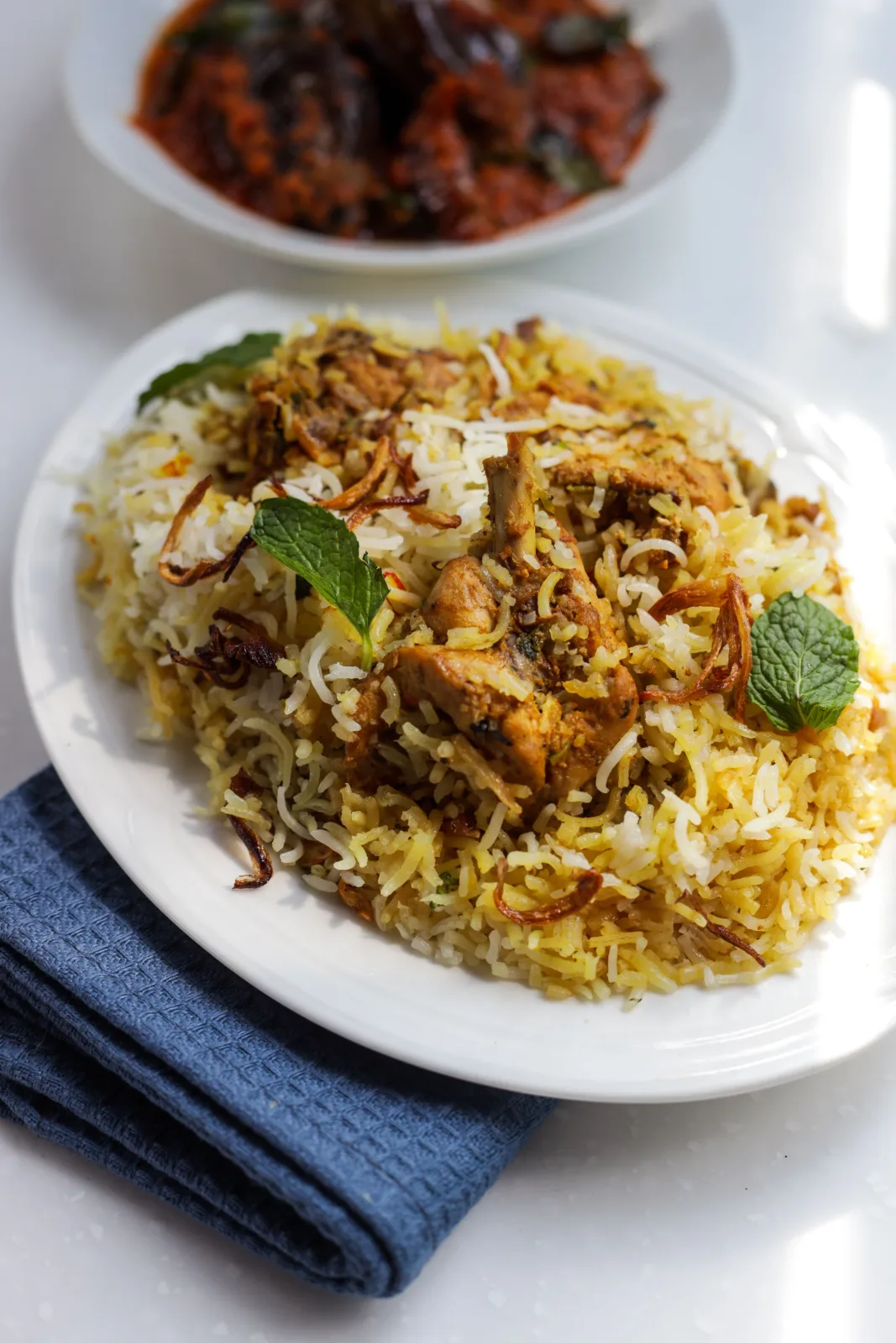 A pot of mutton biryani with saffron rice, tender mutton pieces, fried onions and fresh herbs