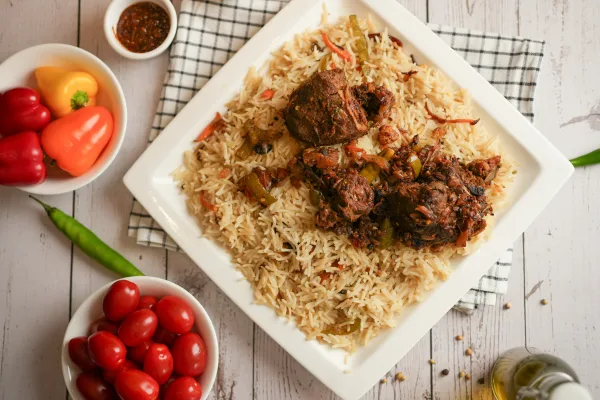A pot of mutton yakhni pulao with golden basmati rice, mutton pieces, fried onions and mint