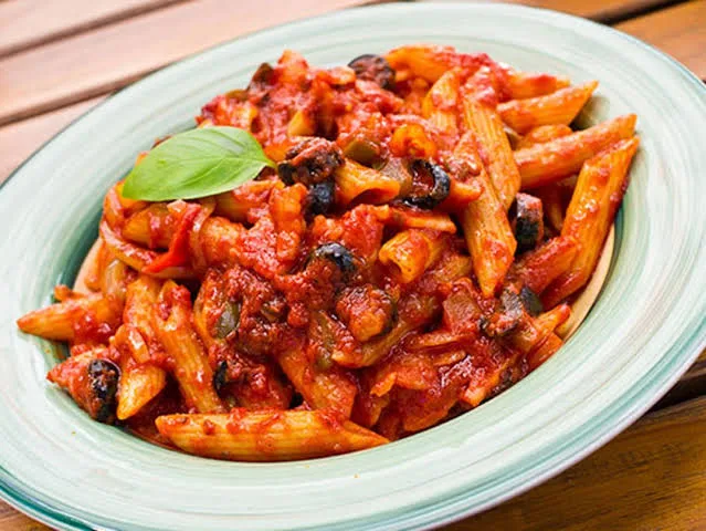 A bowl of penne arrabbiata in a glossy red chilli tomato sauce topped with parsley and cheese