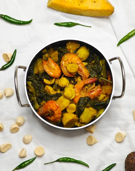 A karahi of prawns in thick tomato masala garnished with ginger and coriander, served with naan and lemon