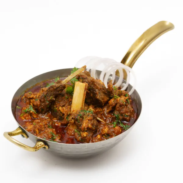 A karahi of glossy Shinwari lamb karahi topped with green chillies, ginger and coriander, served with naan and lemon.